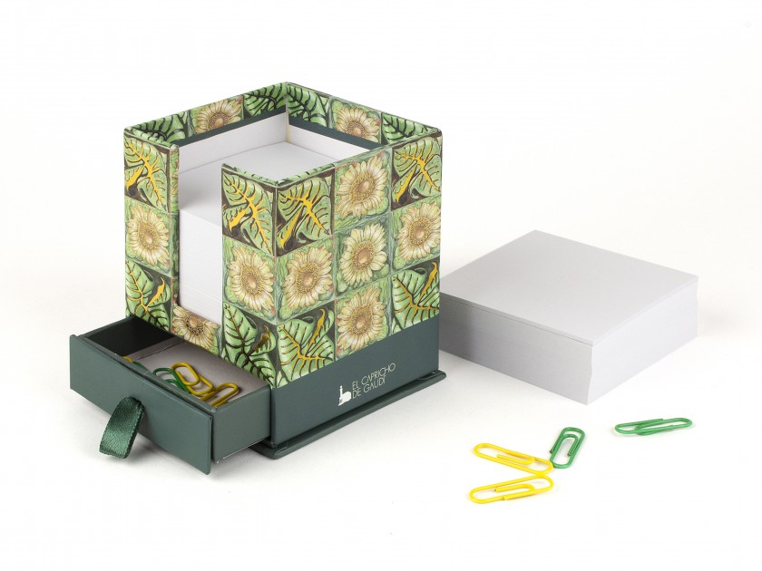 caixa quadrada impresa amb gira-sols i el logotip del Capricho de Gaudí farcida de fulles tipus bloc de notes
