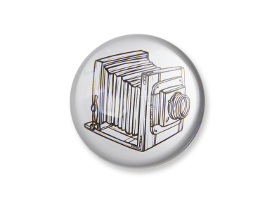 glass paperweight seen from above with an illustration of an old camera inside