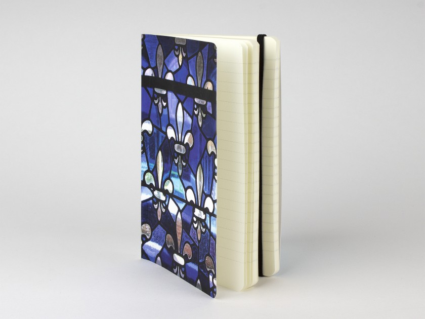 cuaderno visto de frente con una tapa impresa con una flor de lis