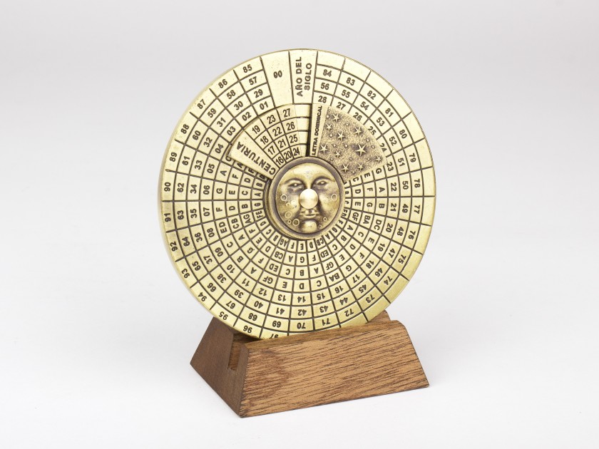Calendrier perpétuel en métal doré posé sur un socle en bois