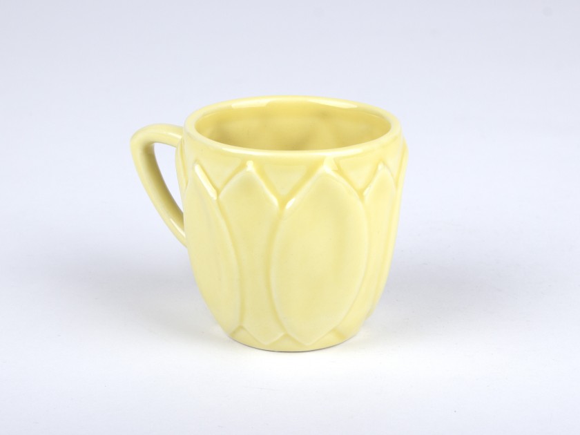 taza de café de cerámica esmaltada amarilla sobre un platillo en forma de girasol