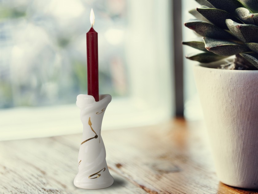 White and gold enamelled ceramic candlestick with a candle